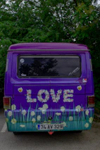 Mobile detailing van with purple logo parked in front of a cozy home.
