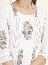 A close-up of a garment featuring intricate floral embroidery patterns with red, green, and blue colors on a white fabric. The design includes vertically aligned lines and floral motifs positioned symmetrically.