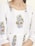 A close-up of a garment featuring intricate floral embroidery patterns with red, green, and blue colors on a white fabric. The design includes vertically aligned lines and floral motifs positioned symmetrically.