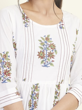 A close-up of a garment featuring intricate floral embroidery patterns with red, green, and blue colors on a white fabric. The design includes vertically aligned lines and floral motifs positioned symmetrically.
