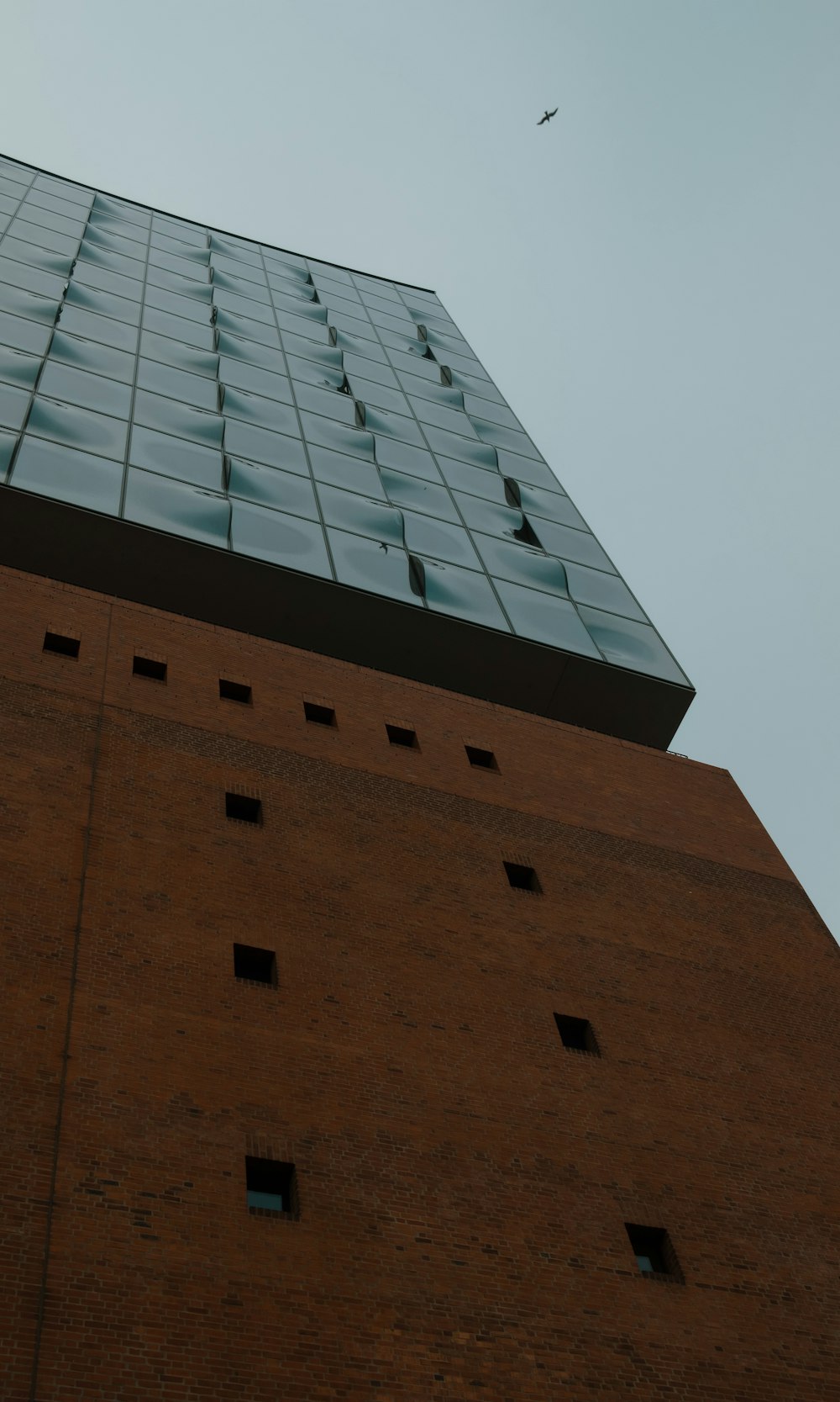 a tall brick building with a plane flying in the sky