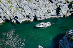 A group of travelers enjoying a boat ride through emerald green waters framed by dramatic limestone cliffs.