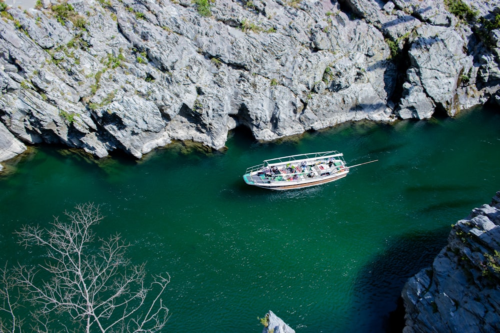 a boat floating on top of a river next to a rocky cliff