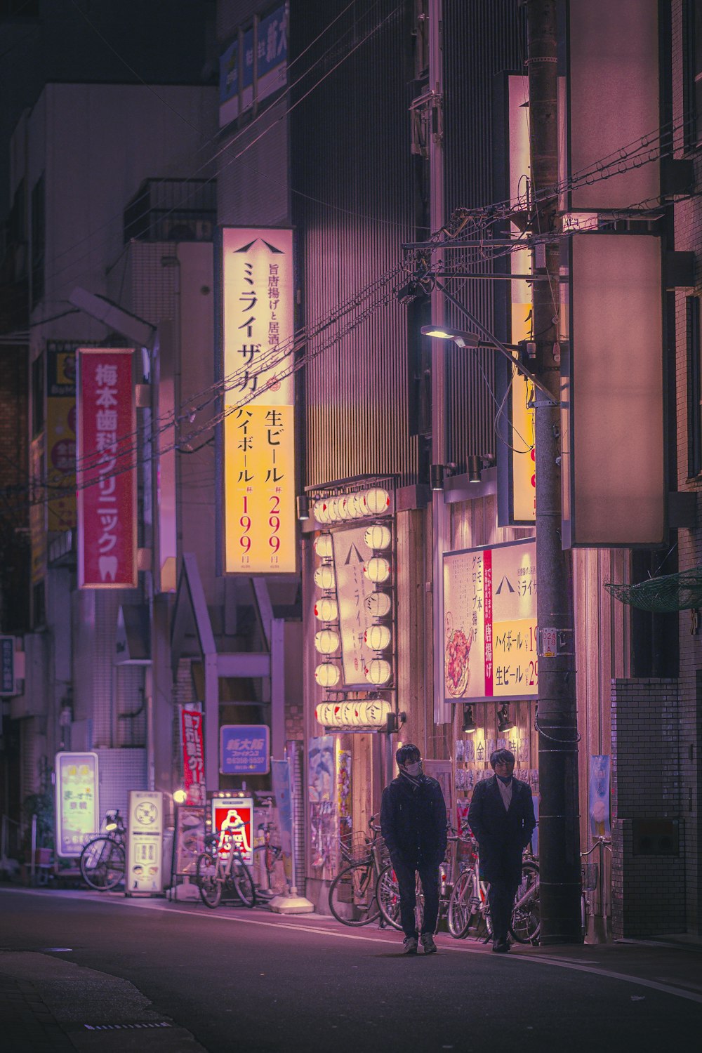 a couple of people walking down a street at night