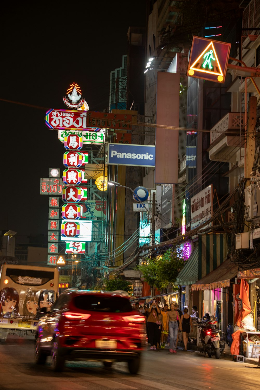 a red car driving down a street next to tall buildings