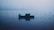 Fishing boat gliding over calm river waters at dawn with mist rising.