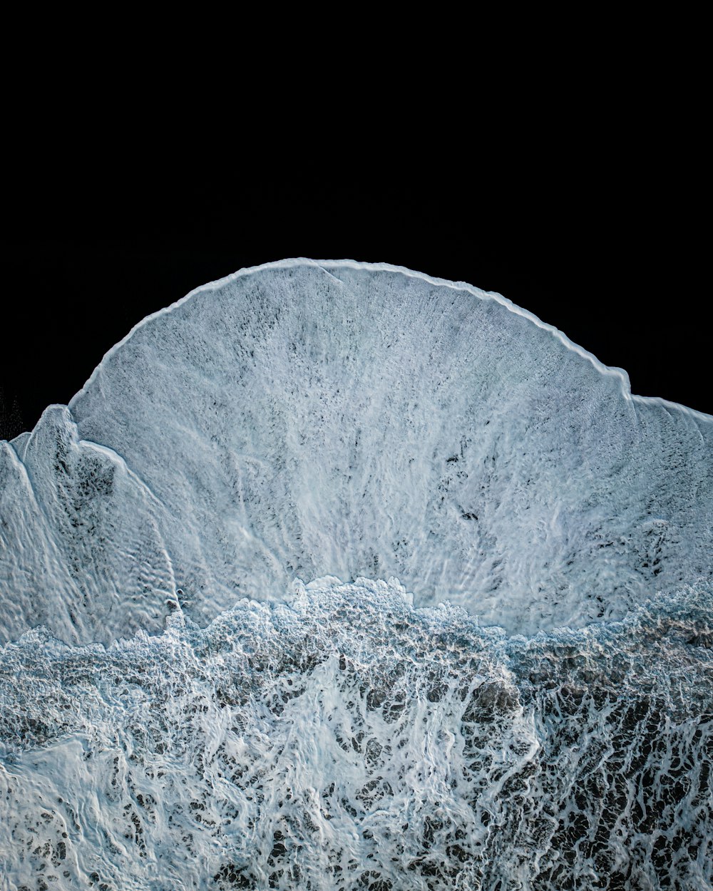 a large wave crashing into the ocean on a black background