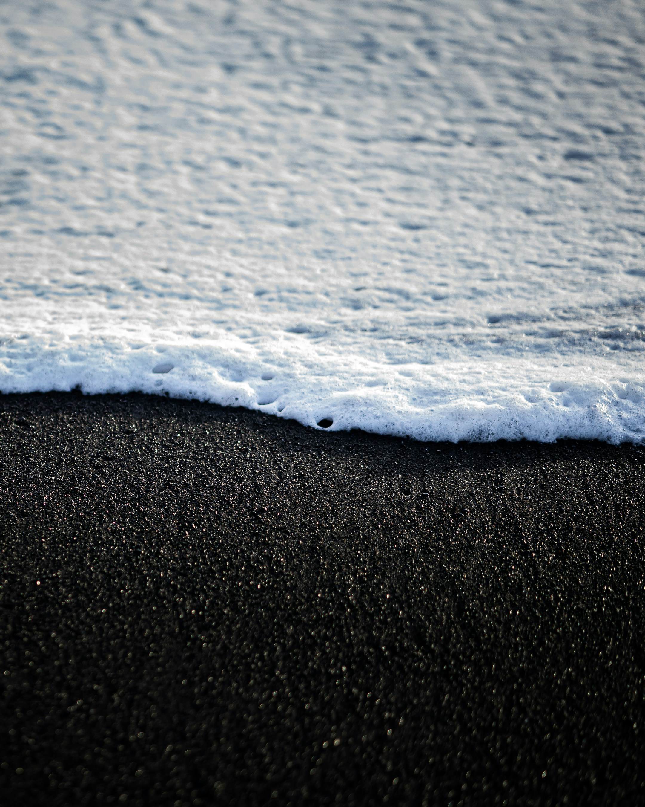 a black sand beach with a wave coming in