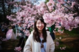 A family smiling together in front of cherry blossoms in Japan during spring.