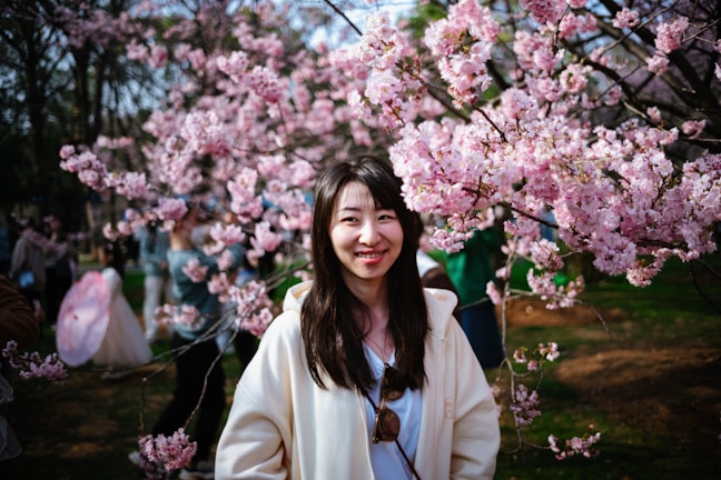 A family smiling together in front of cherry blossoms in Japan during spring.