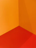 Painter carefully detailing a wall corner with vibrant orange paint.