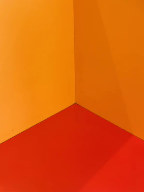 Painter carefully detailing a wall corner with vibrant orange paint.