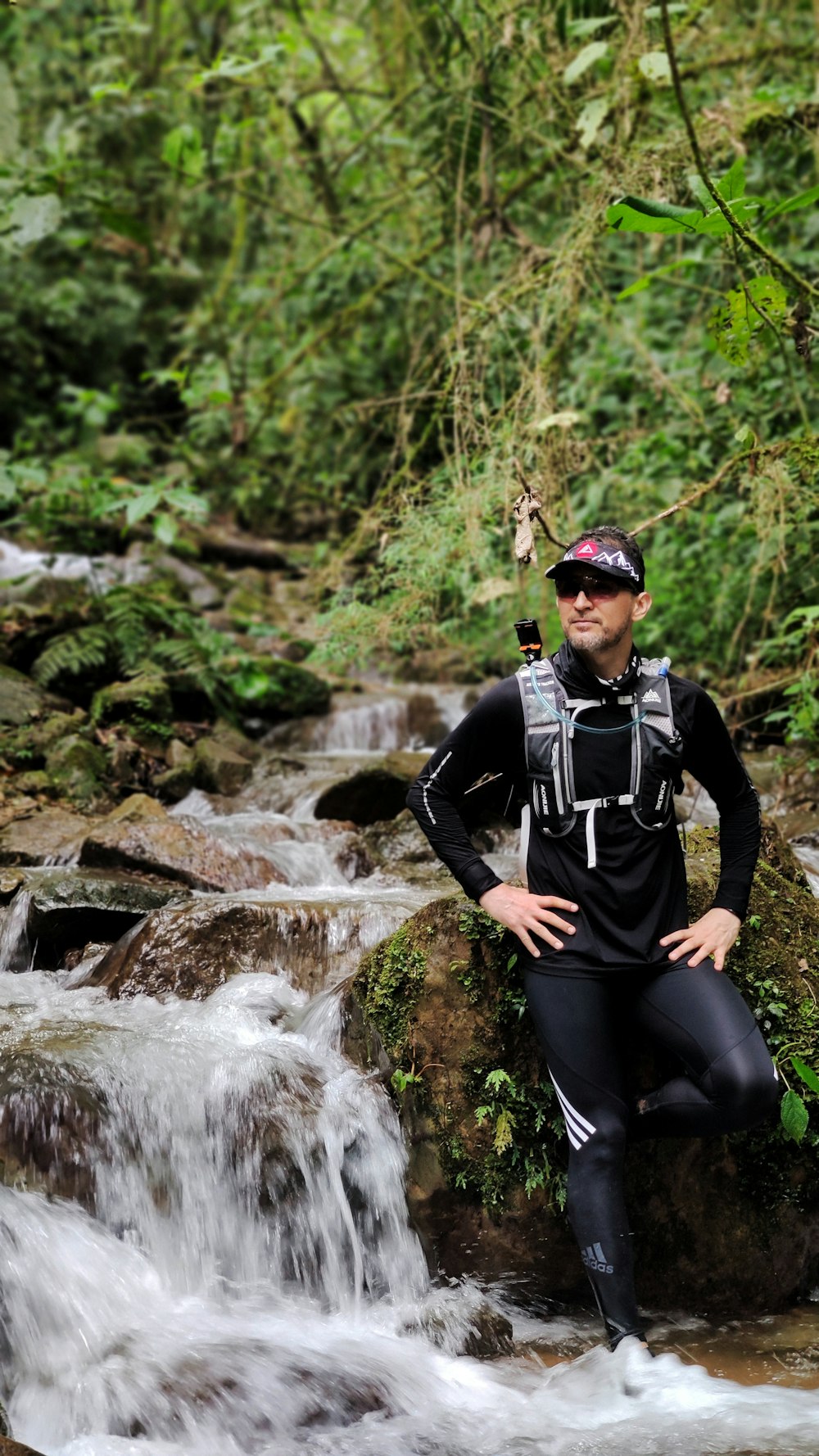 a man in a wet suit standing on a rock next to a river