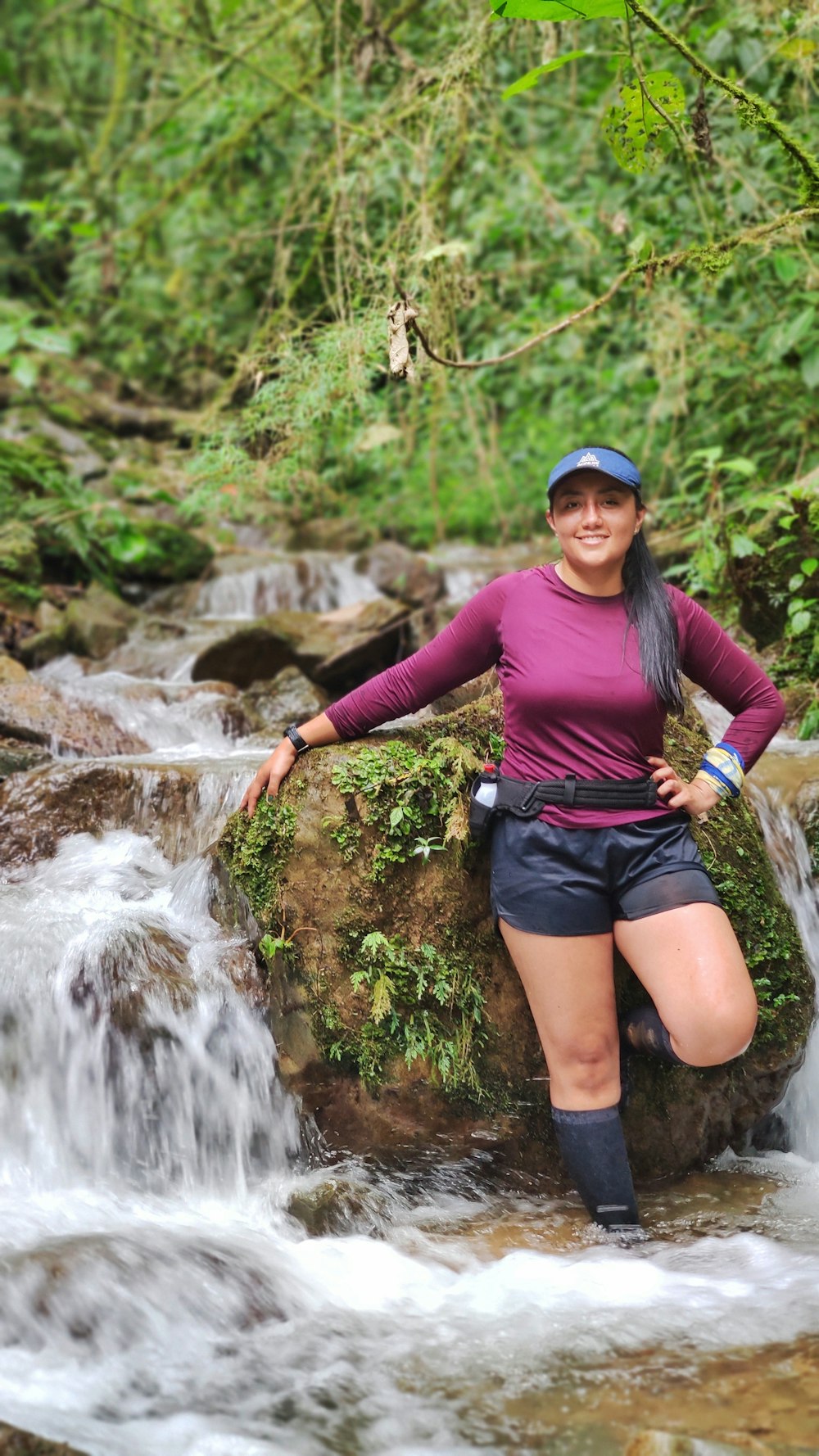 a woman standing on a rock in a stream