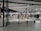 A modern clothing store with mannequins displaying beige and green outfits. The spacious, well-lit interior features neatly arranged racks of clothes and showcases a minimalist design. Spotlights hang from the ceiling, illuminating the display areas.