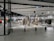 A modern clothing store with mannequins displaying beige and green outfits. The spacious, well-lit interior features neatly arranged racks of clothes and showcases a minimalist design. Spotlights hang from the ceiling, illuminating the display areas.