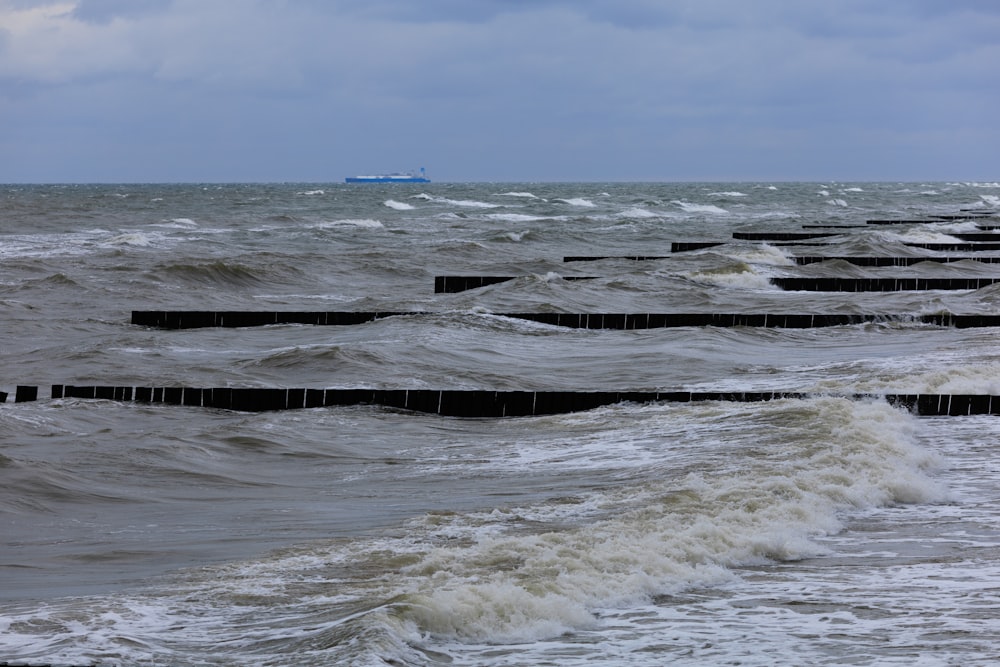 a row of wooden posts sitting in the middle of a body of water