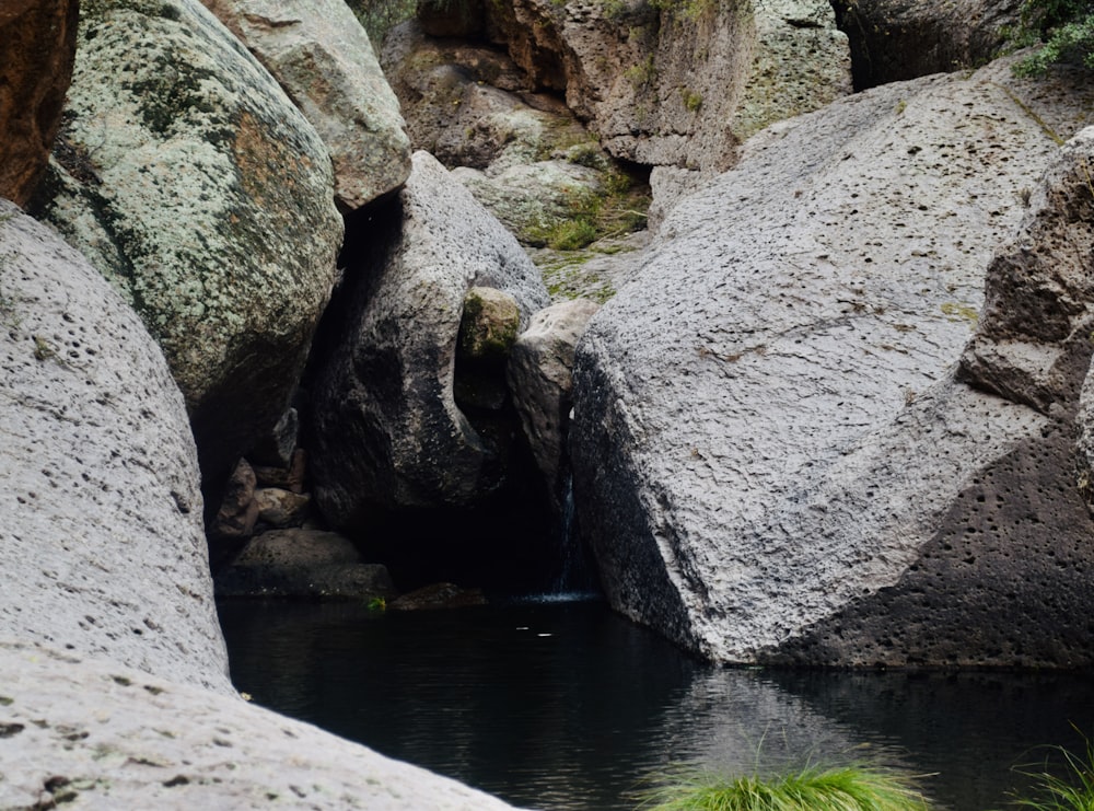 Un pequeño charco de agua rodeado de grandes rocas