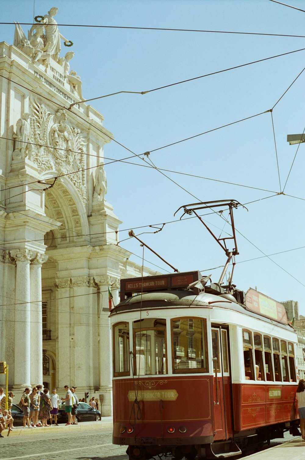 a red and white trolley car traveling down a street