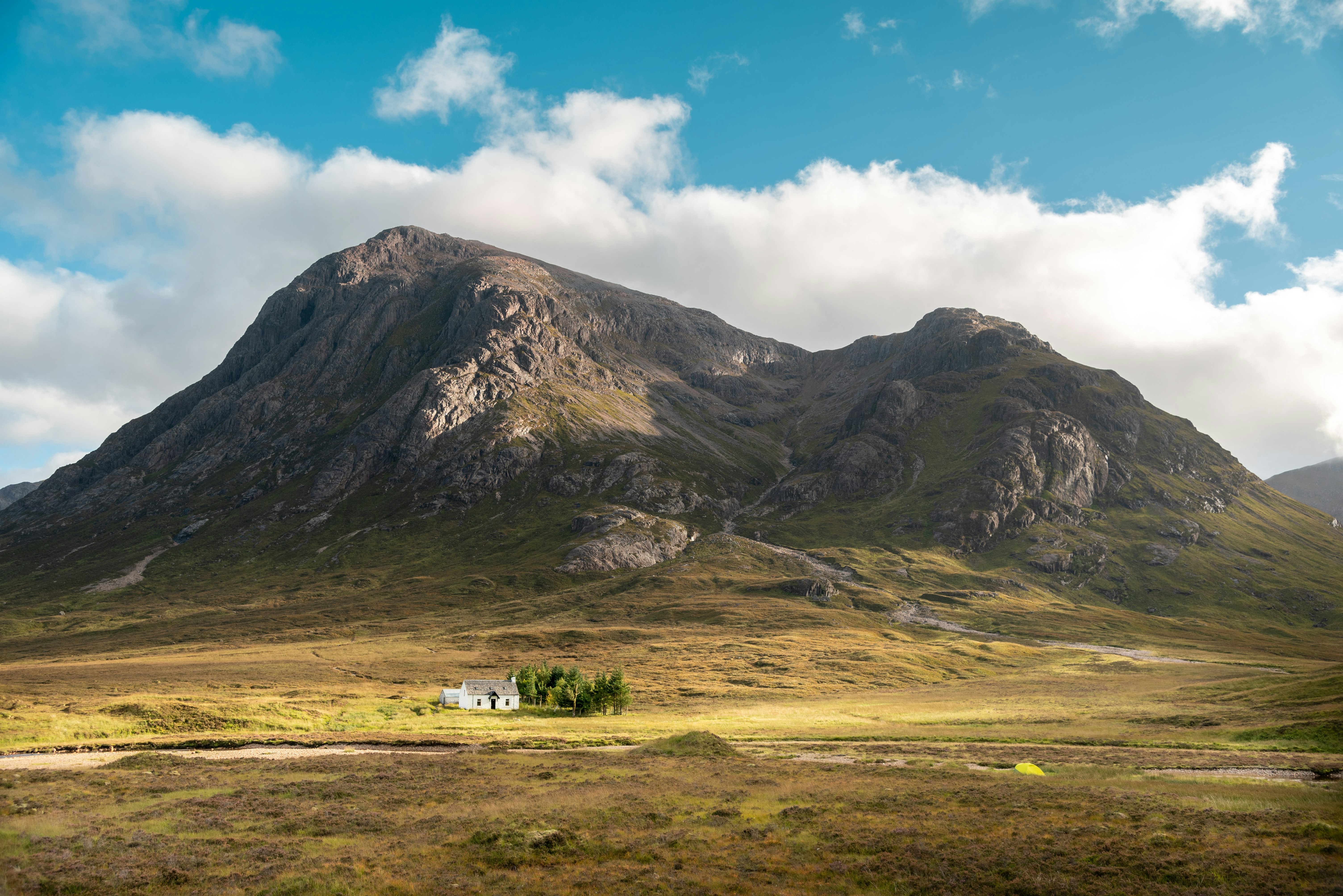 a house in the middle of a field with a mountain in the background