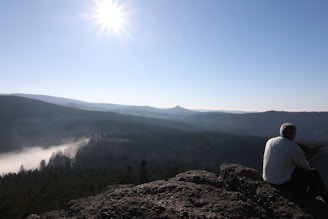 A serene landscape with a person sitting on a bench, gazing at the horizon, symbolizing reflection and hope.