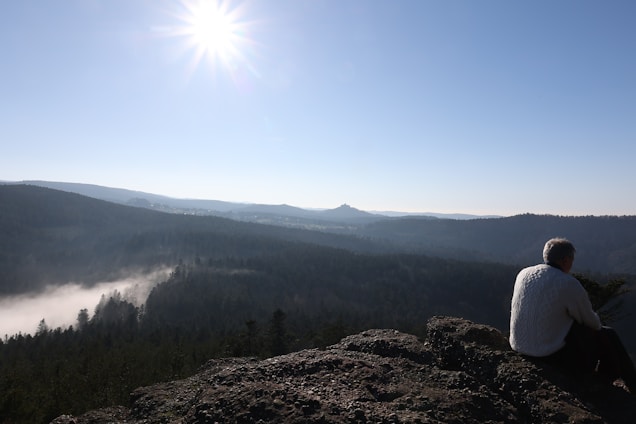 A serene landscape with a person sitting on a bench, gazing at the horizon, symbolizing reflection and hope.