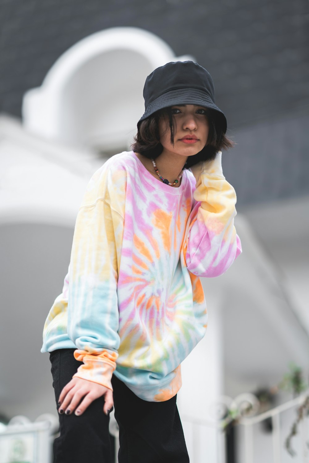 a woman wearing a tie dye shirt and black hat