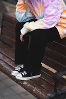 A sporty hoodie with thumbholes, laid out on a wooden bench.
