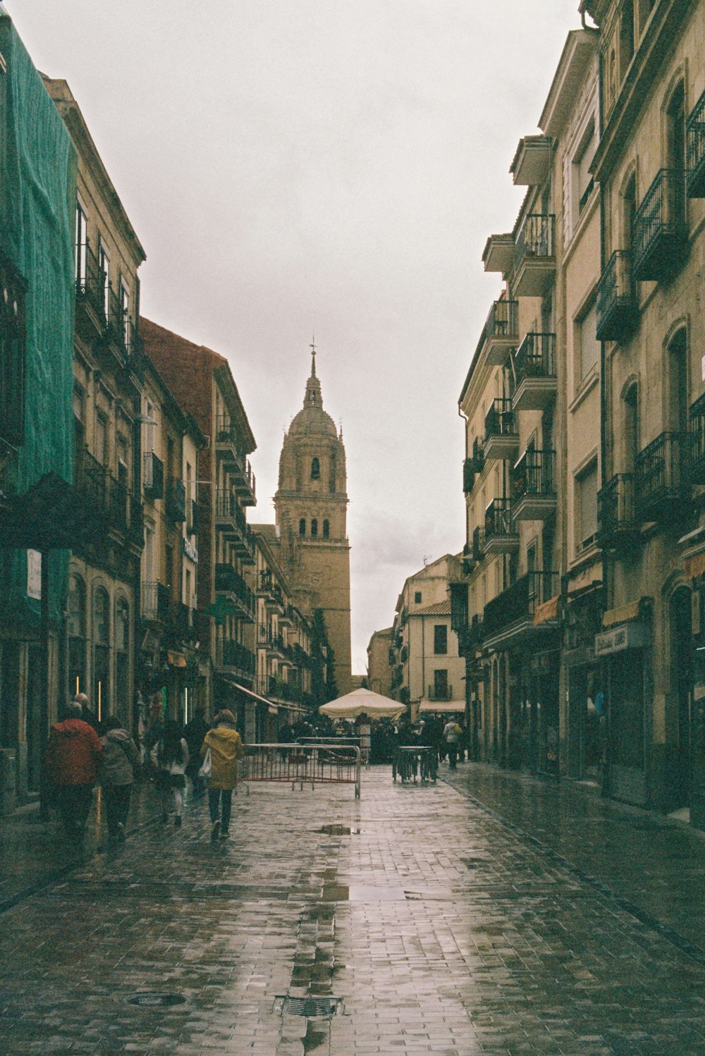 a rainy day in a city with people walking down the street