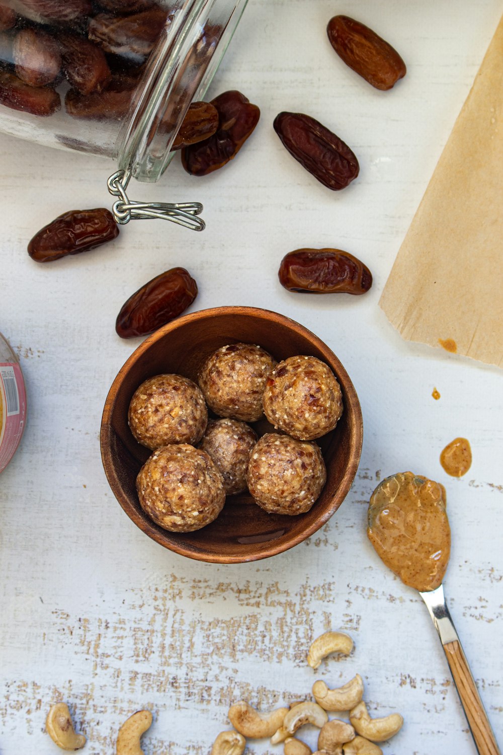 a wooden bowl filled with nuts next to a jar of nuts