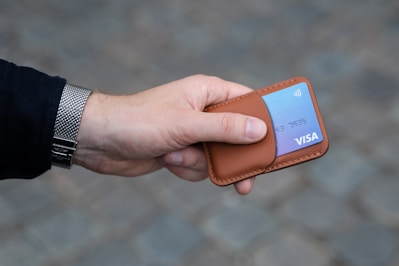 a hand holding a wallet with a credit card in it
