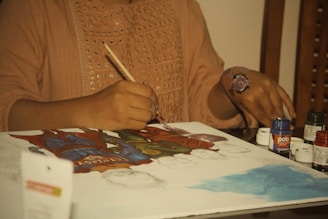 a woman sitting at a table painting a picture