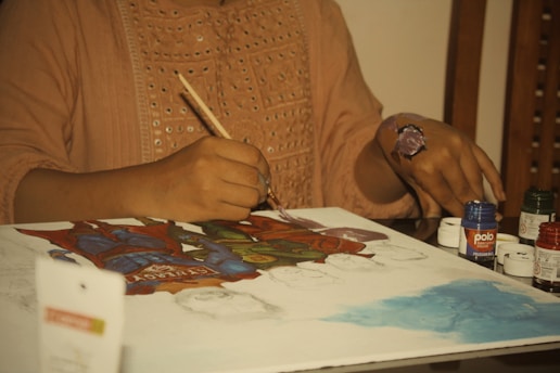 a woman sitting at a table painting a picture