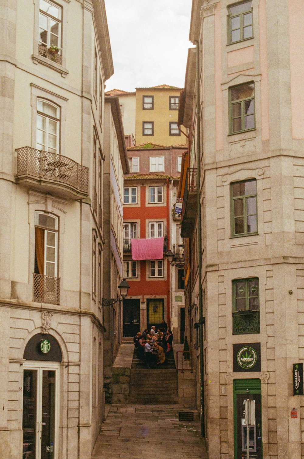 a group of people sitting at a table in a narrow alleyway