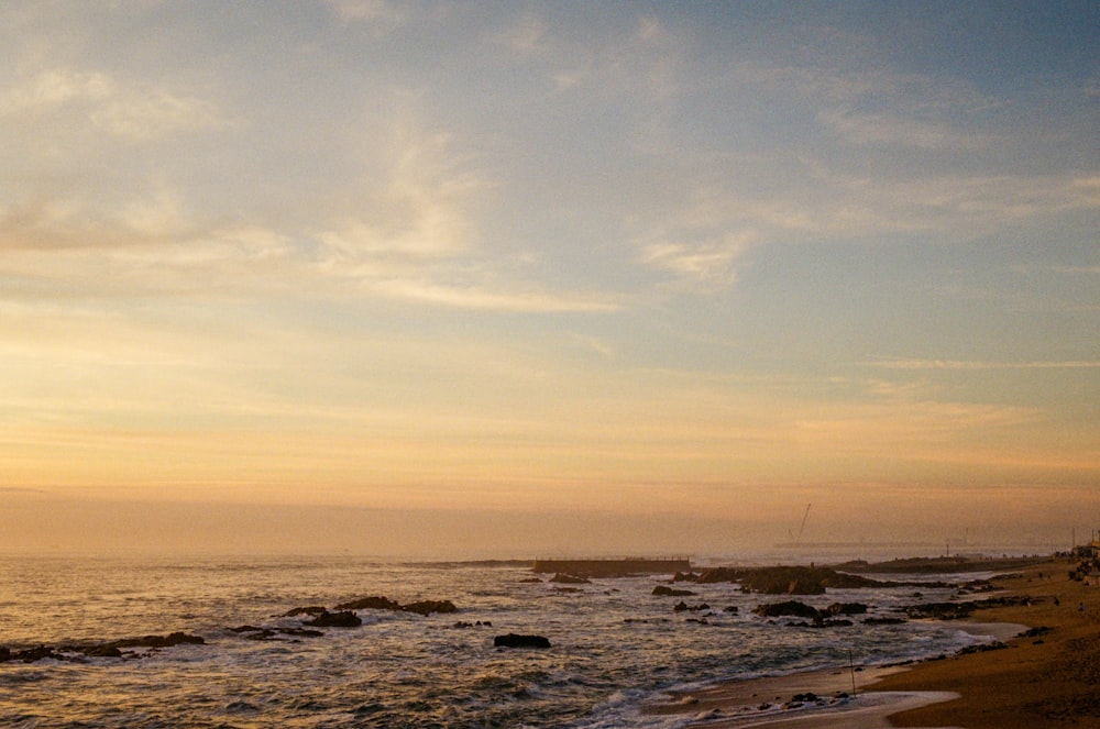 a couple of people walking along a beach next to the ocean