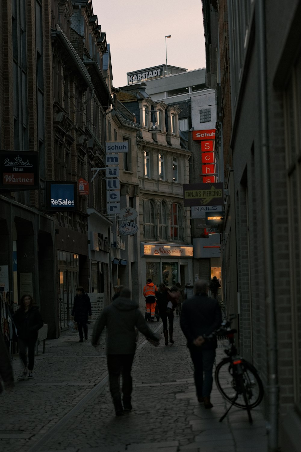 a group of people walking down a street next to tall buildings