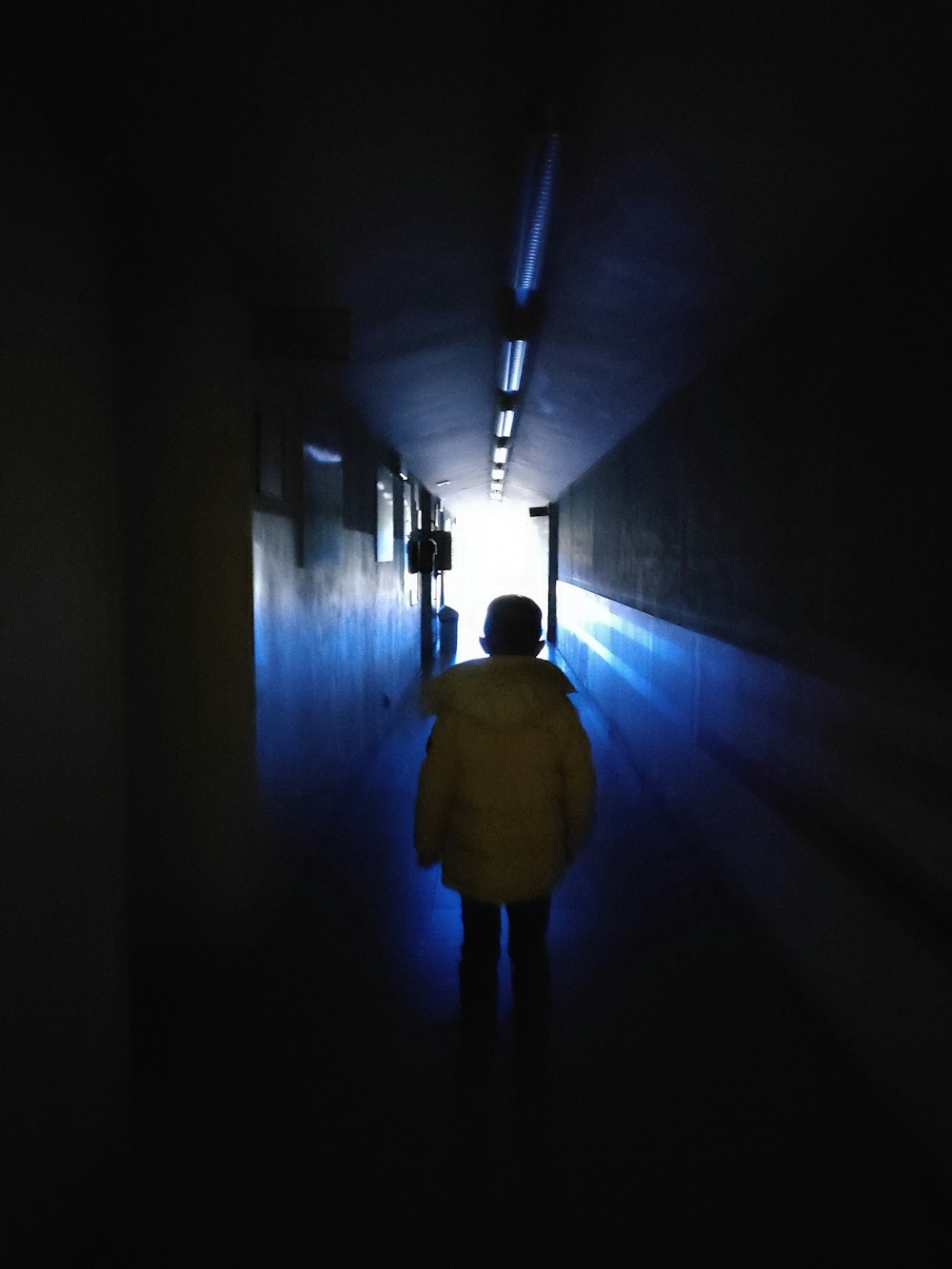 a person in a yellow jacket walking down a dark hallway