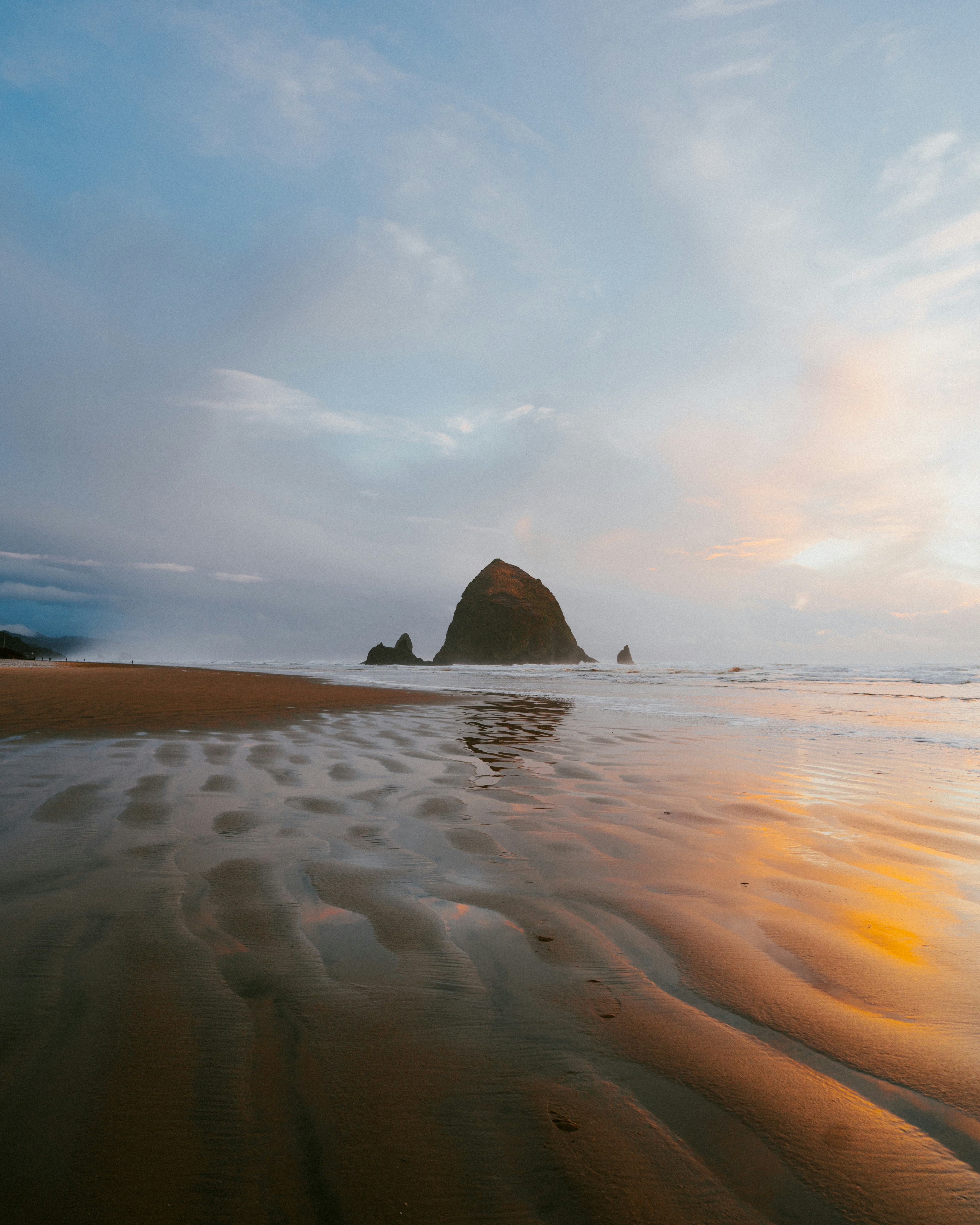 a sandy beach with a rock in the distance