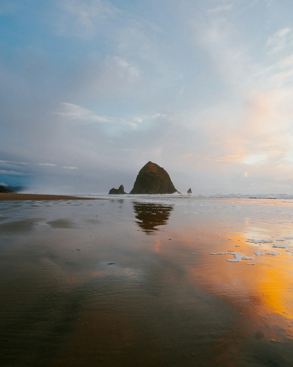 a beach with a large rock in the distance