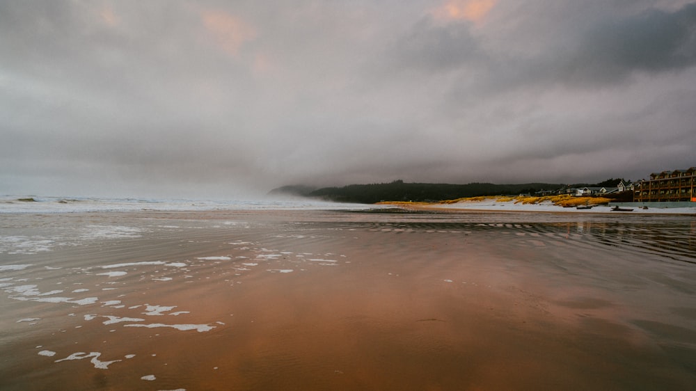 a cloudy day at the beach with the tide coming in