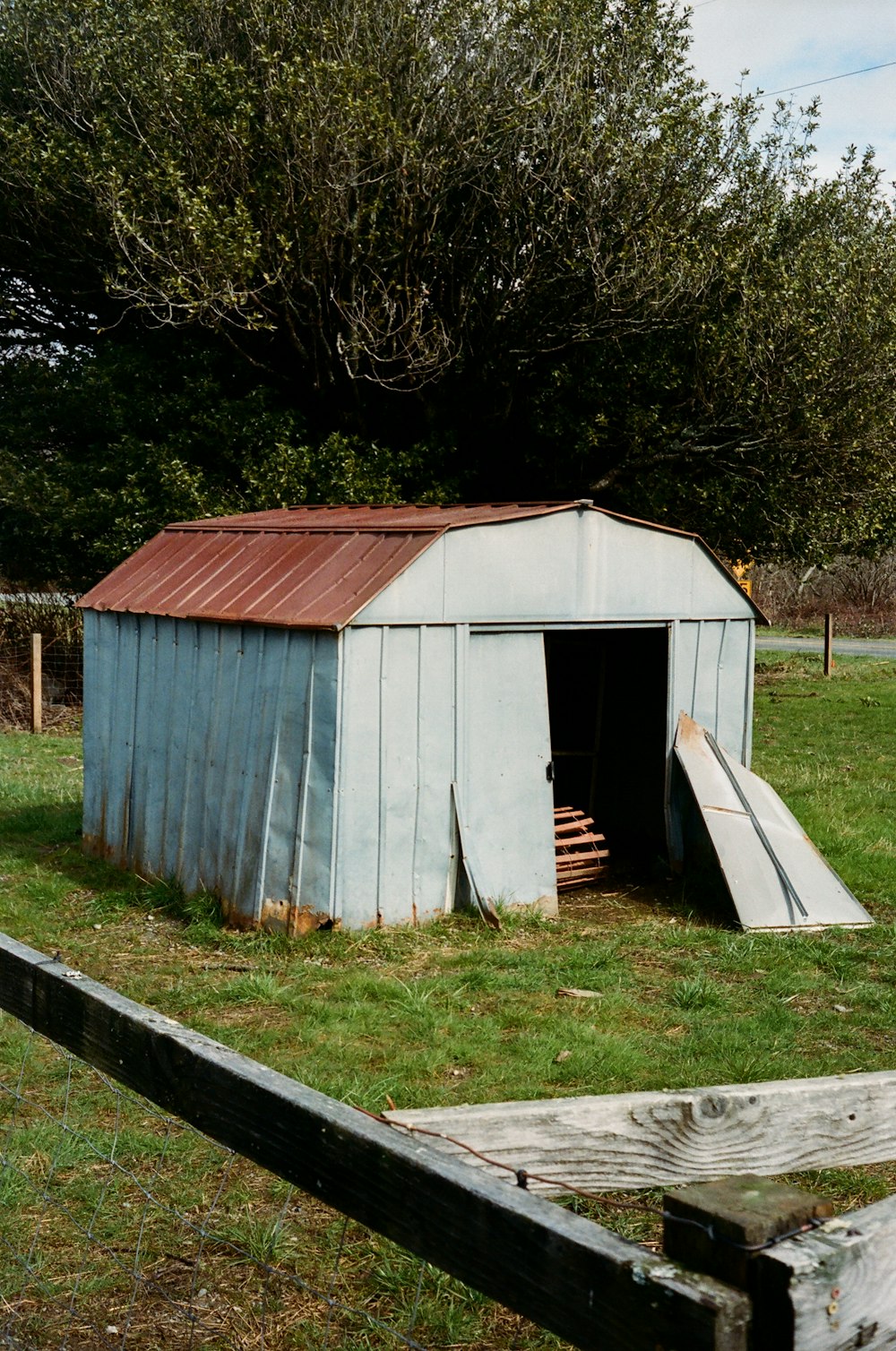 a small blue shed with a slide in it