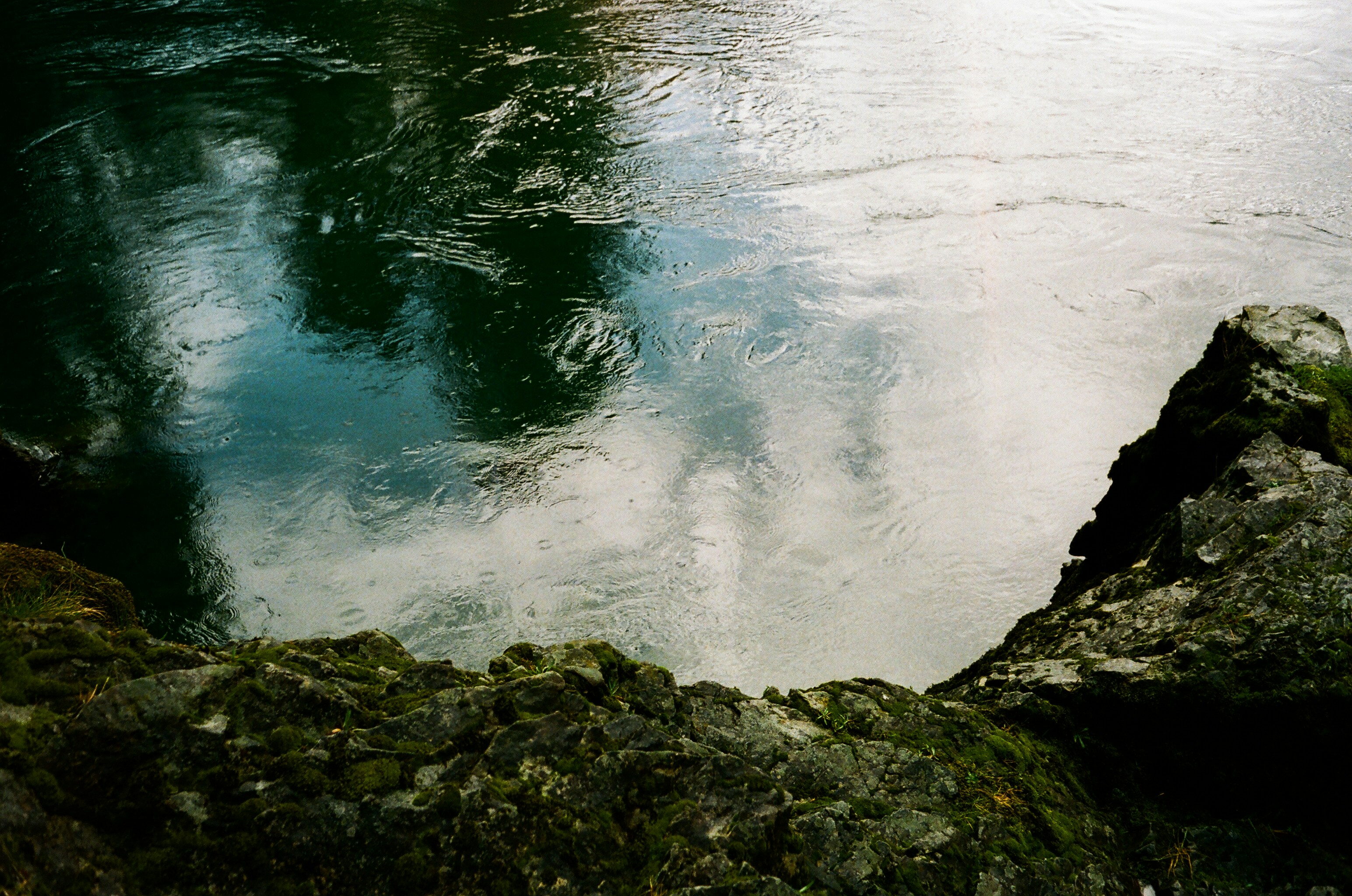 a body of water surrounded by rocks and grass