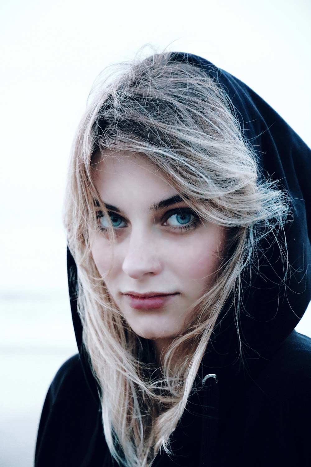 a woman with blue eyes and a black hoodie