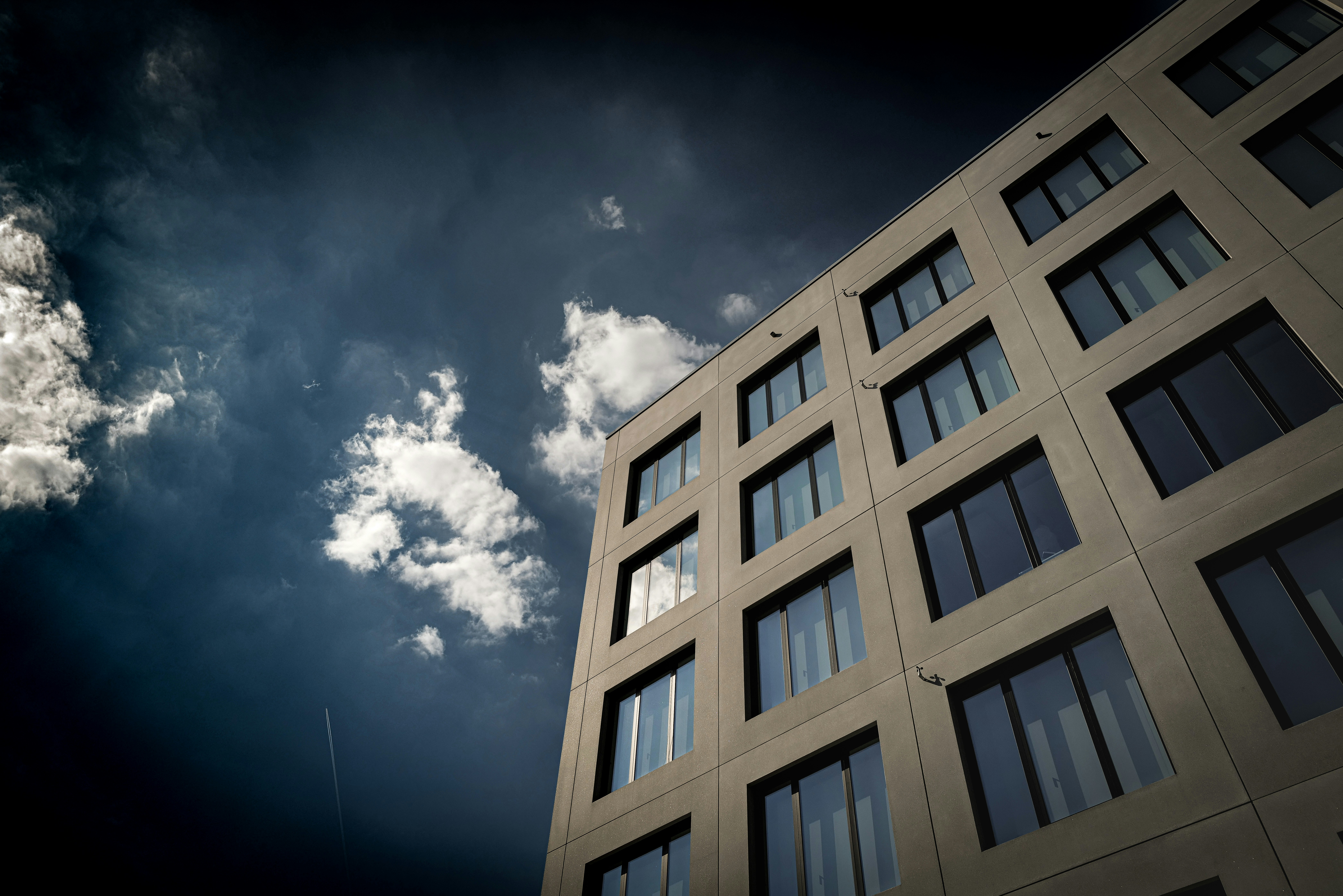 a tall building with lots of windows under a cloudy sky