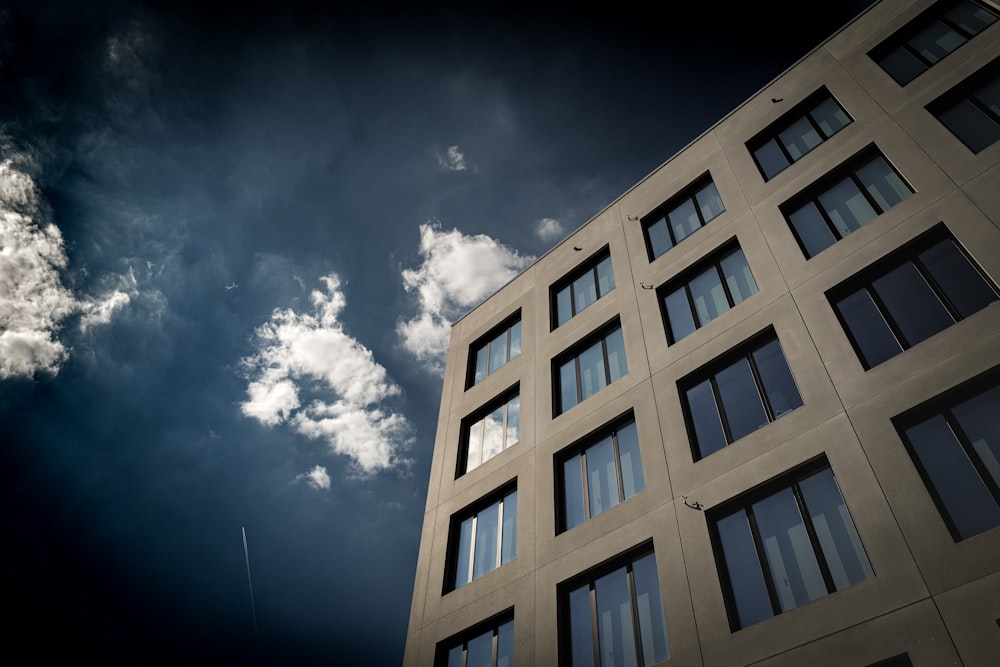 a tall building with lots of windows under a cloudy sky