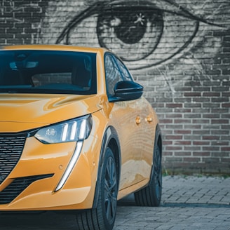 a yellow car parked in front of a brick wall