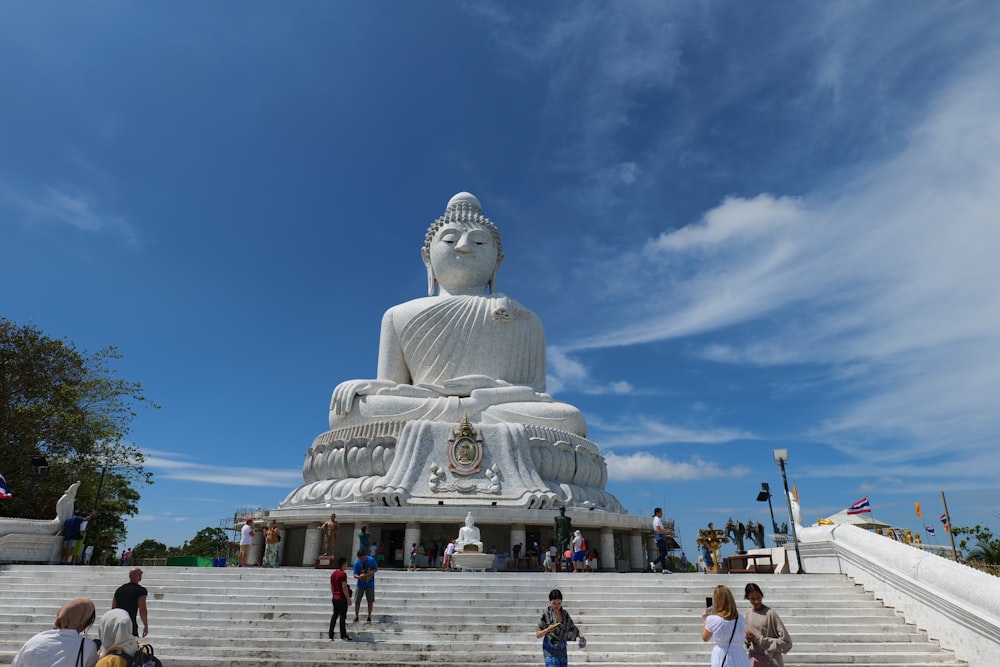 Eine große weiße Buddha-Statue sitzt auf einer Reihe von Stufen