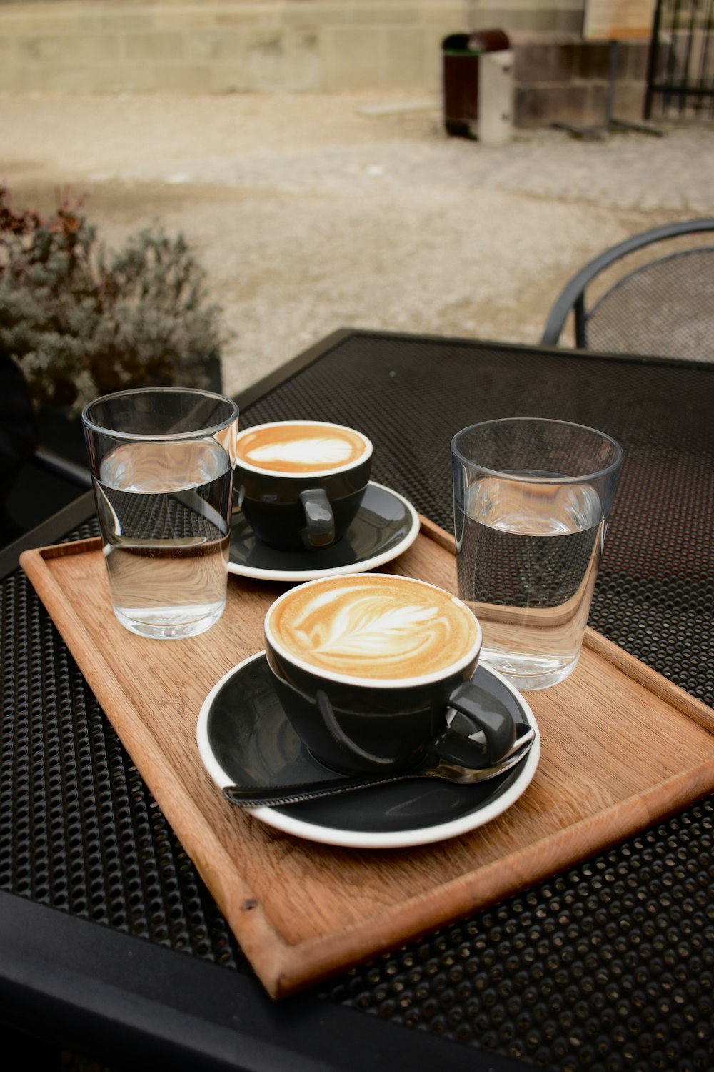a wooden tray topped with two cups of coffee