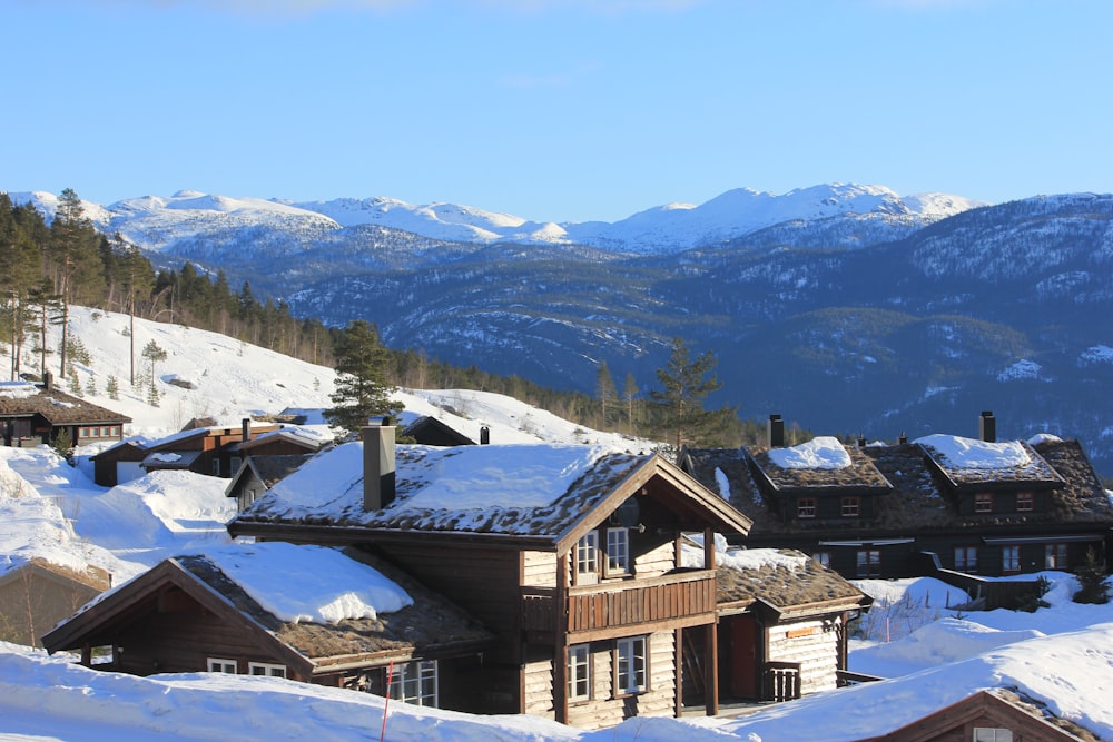 a snow covered mountain range with houses in the foreground