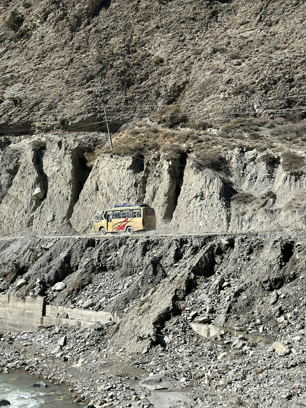 a bus driving down a road next to a cliff